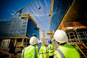 A group of construction workers looking at a crane.