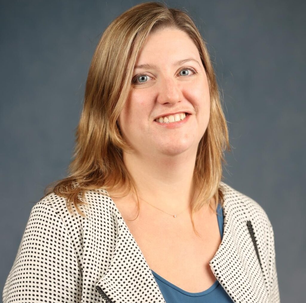 A smiling woman in a blue jacket.