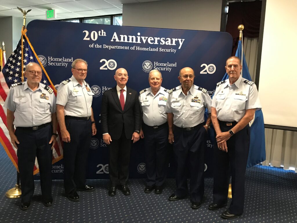 A group of men in uniform standing in front of an american flag.