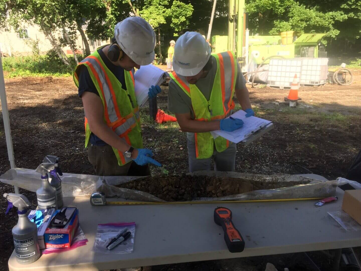 Workers examining soil sample on site.